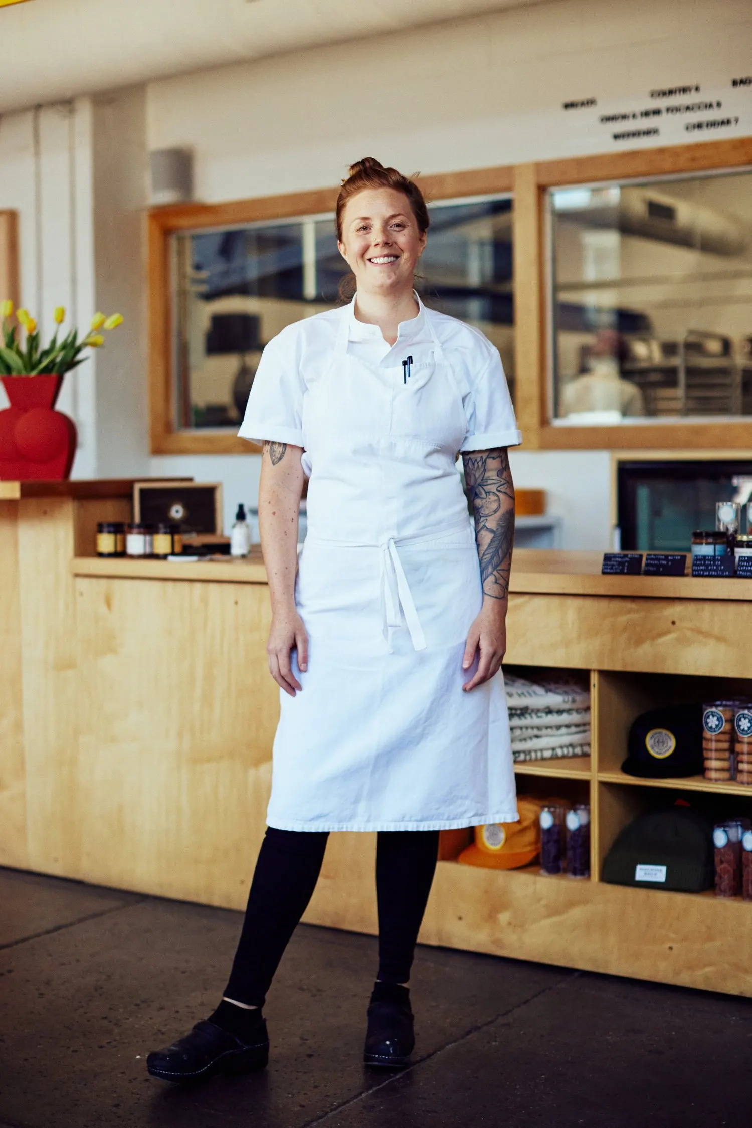 A smiling chef in her apron at the restaurant counter