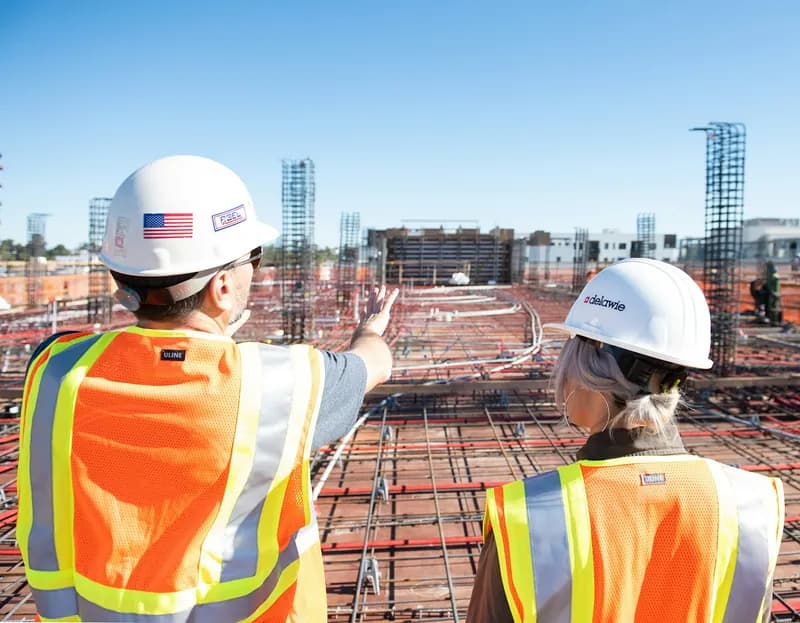Two site managers in hi-vis looking over a construction site
