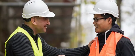 Two construction workers shaking hands on site