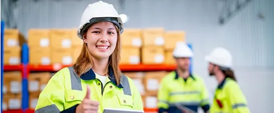 A smiling warehouse worker in hi-vis with her team